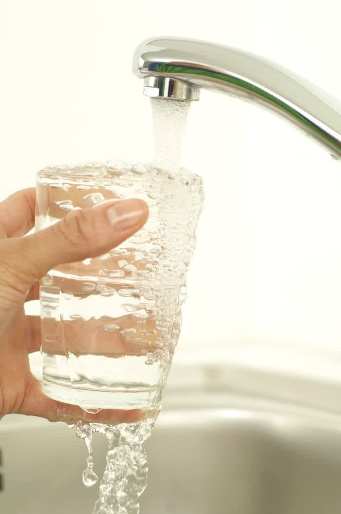 A hand holding a glass under a running kitchen tap