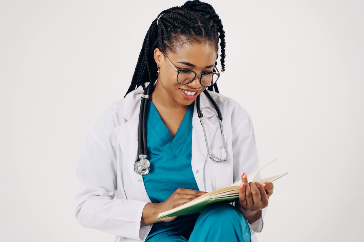 Smiling female doctor with stethoscope reading medical documents