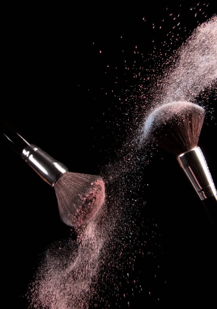 Makeup brushes releasing a cloud of powder