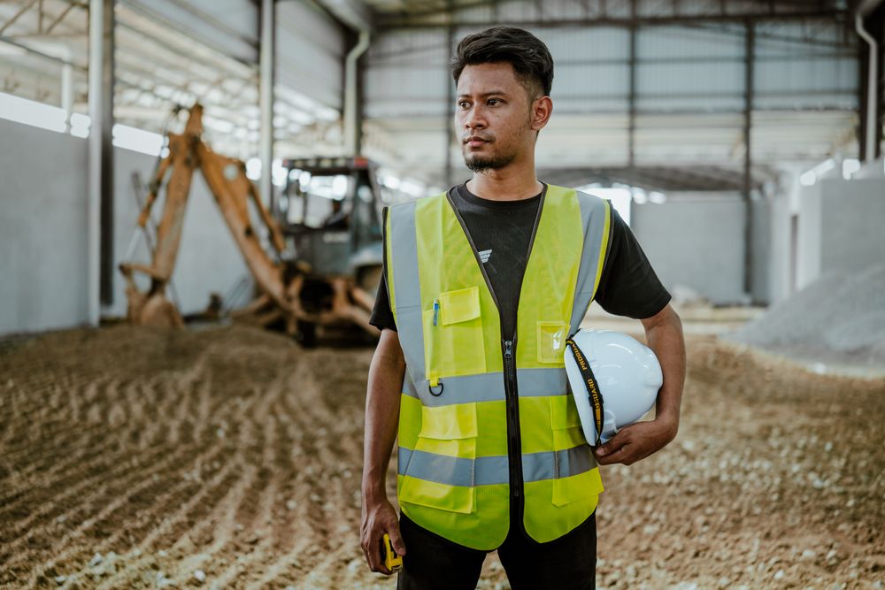 Portrait of a construction worker in safety gear holding a helmet
