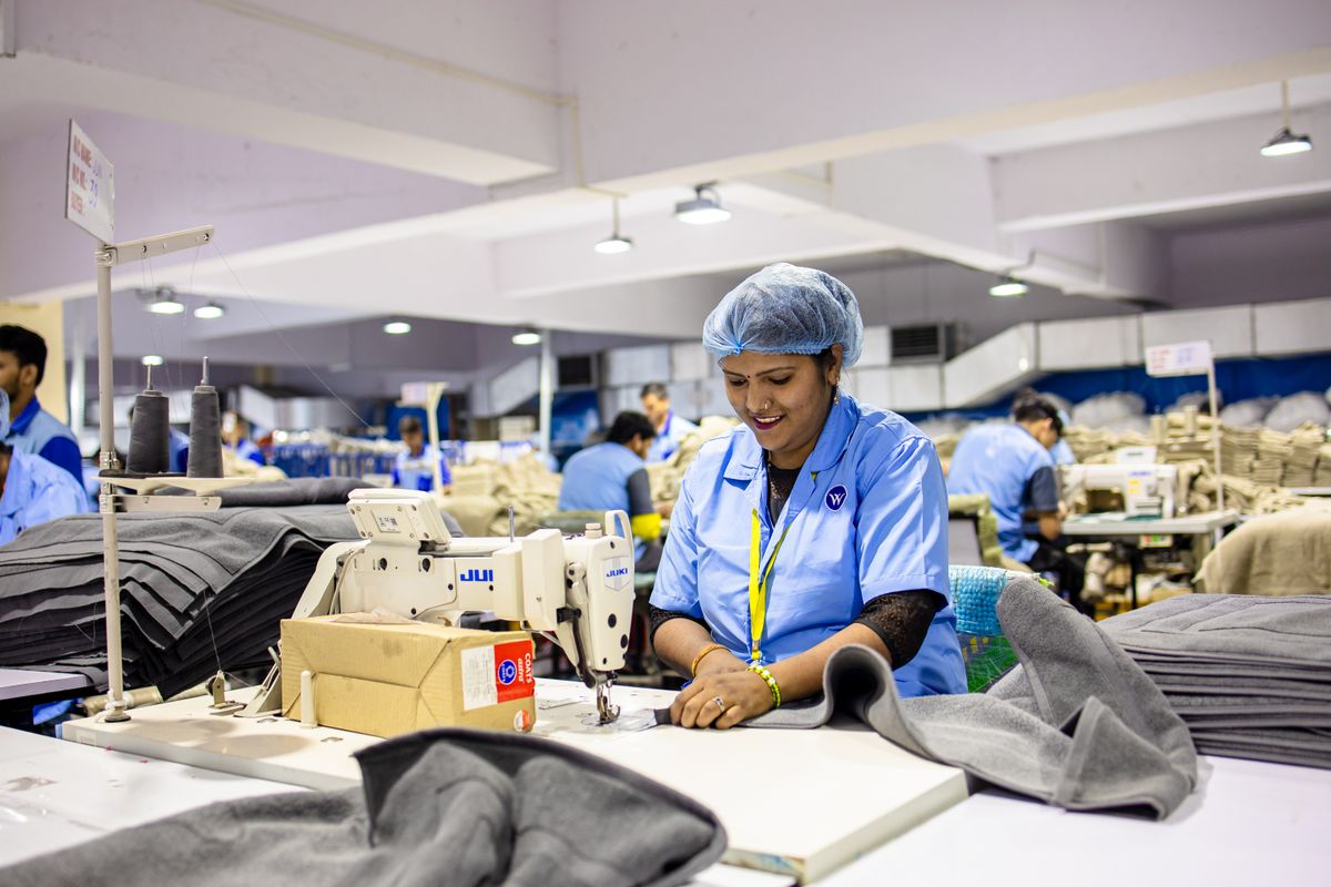 Smiling factory workers operate sewing machines