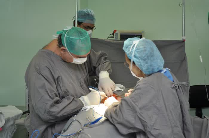 Surgeons in gray scrubs at work in an operating room