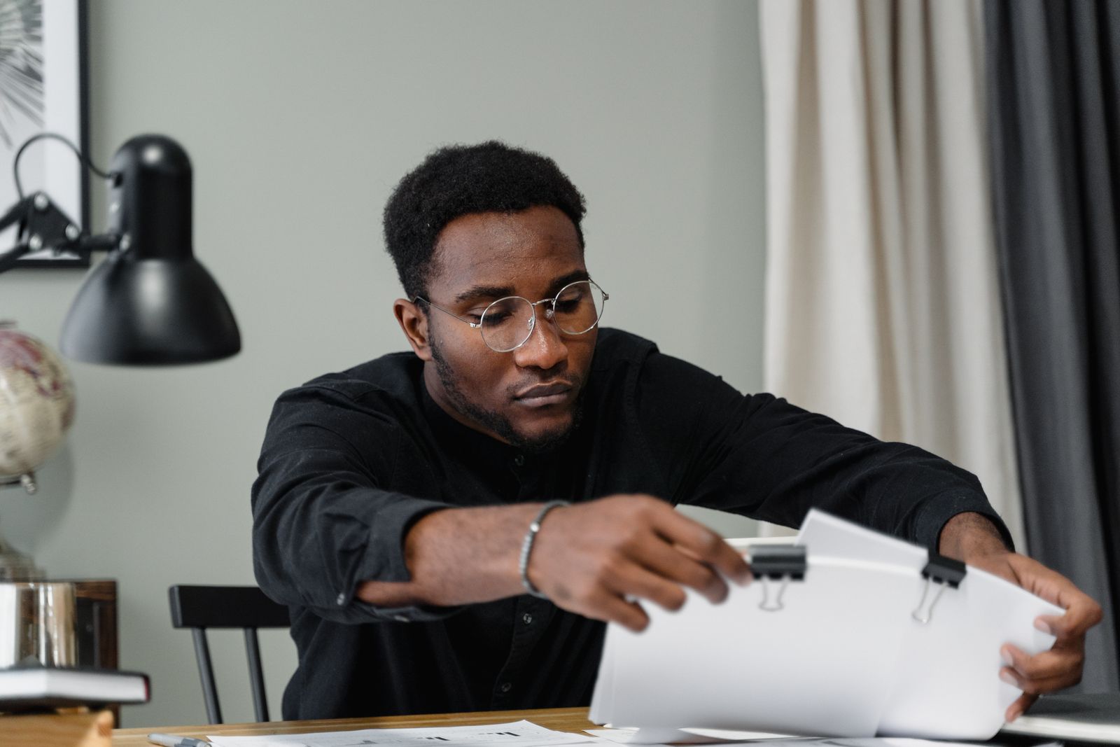 Professional man with glasses reviews documents at a desk in an office setting