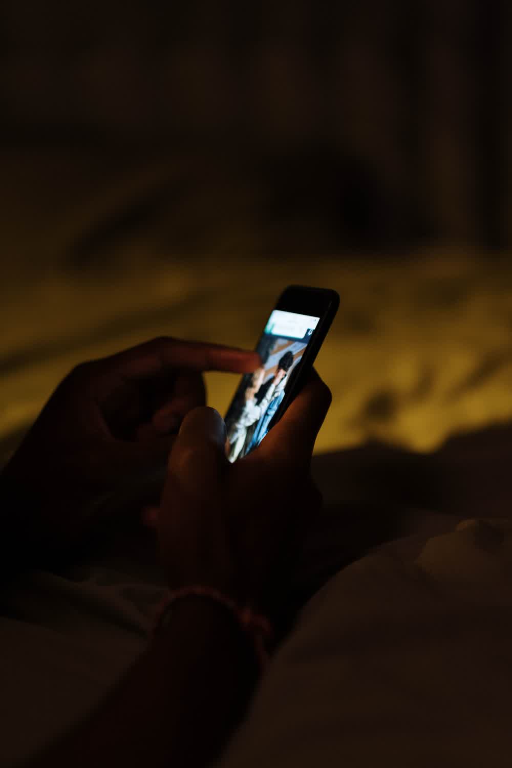 Hands holding a lit smartphone in a dark room