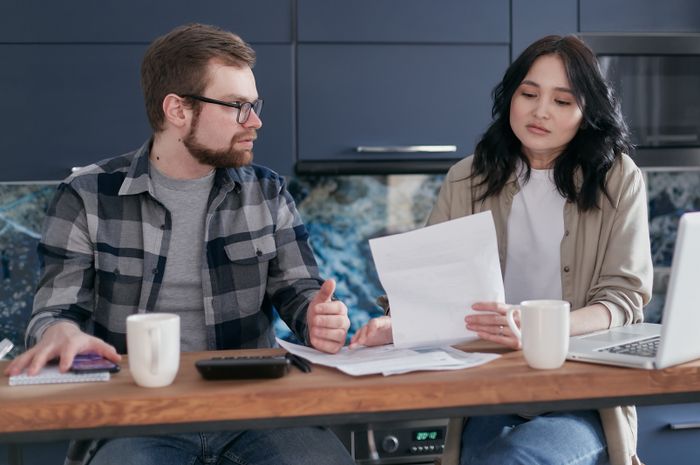 A couple sits at a table reviewing financial documents