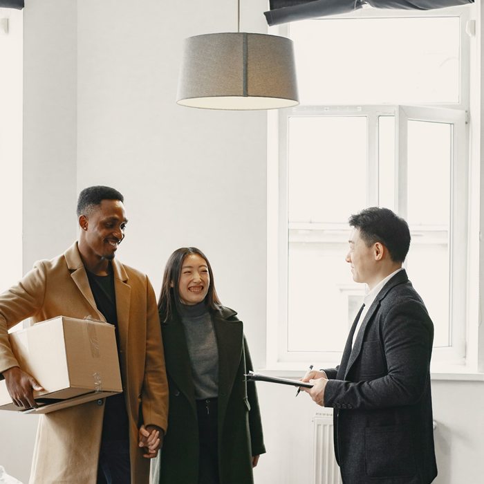 A diverse couple joyfully receives keys to their new home from a real estate agent