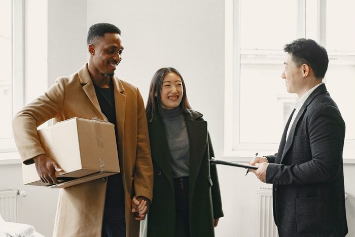 A diverse couple joyfully receives keys to their new home from a real estate agent
