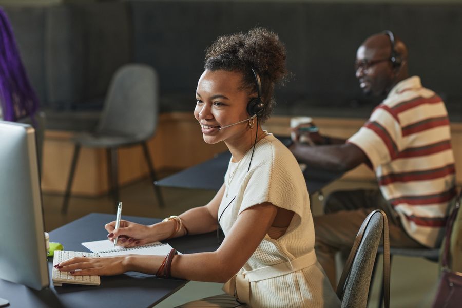 Cheerful woman in a call center using a headset and computer while