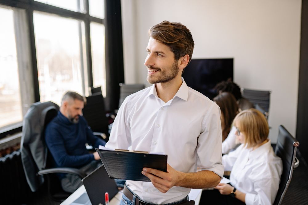 Bearded man in white dress shirt holding a clipboard