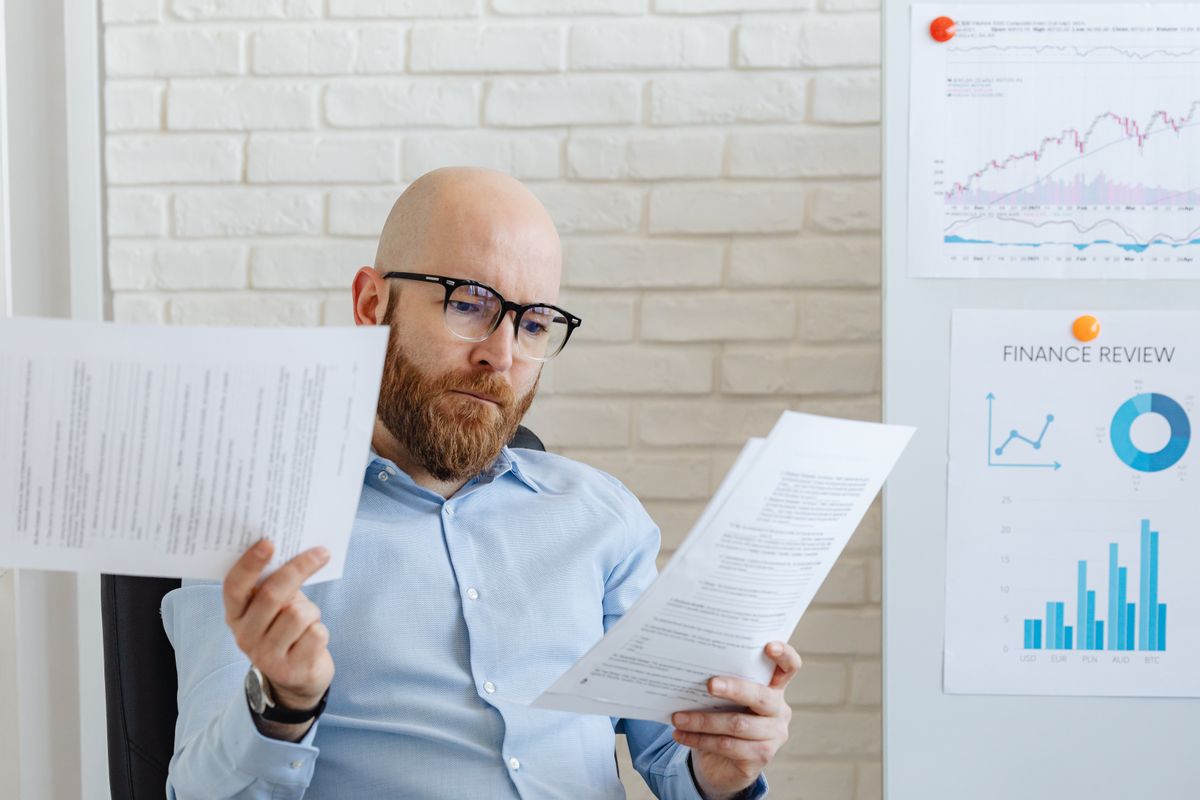 Bald bearded businessman reading financial documents in modern office setting