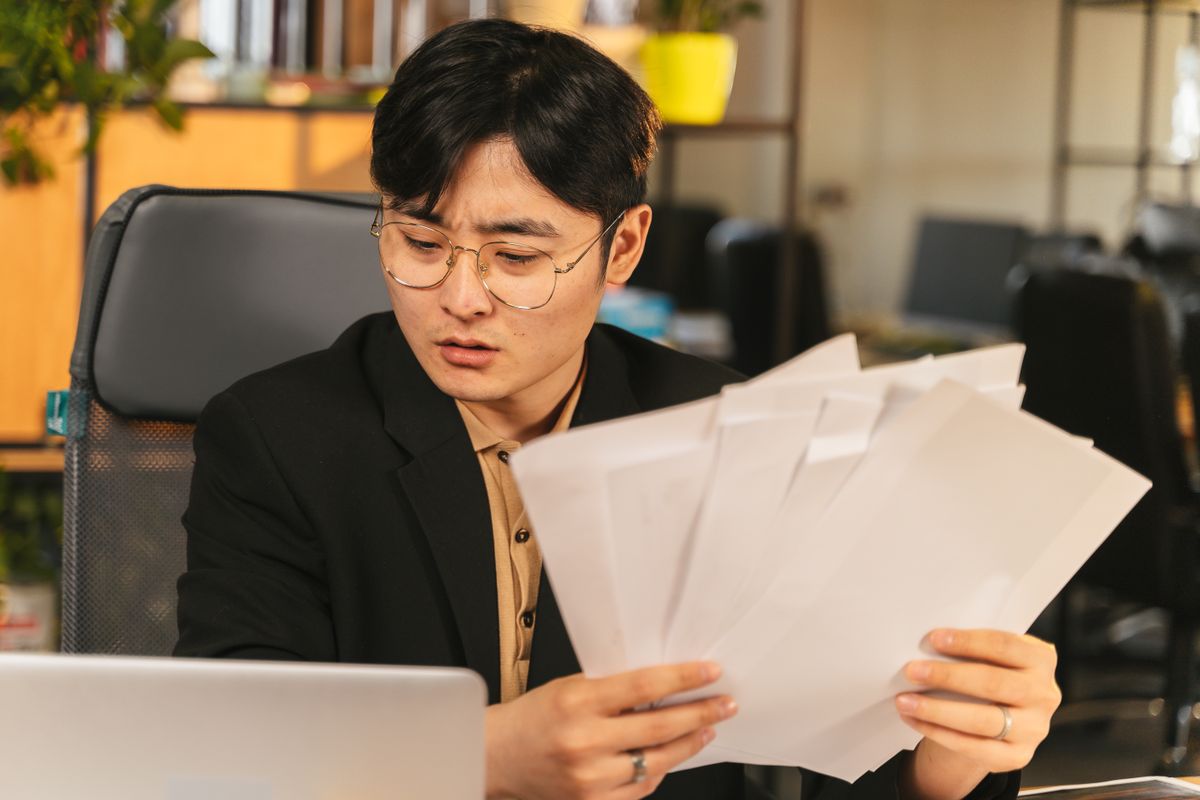 Businessman in glasses reviewing paperwork in a modern office setting
