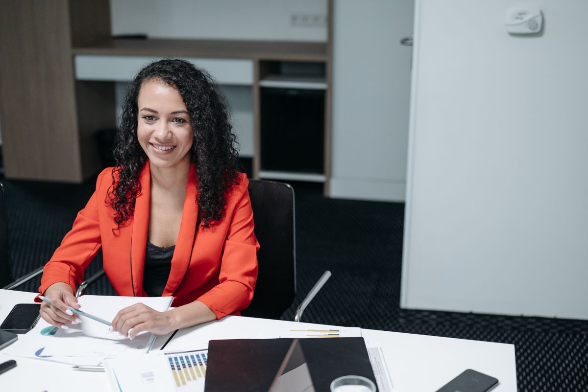Smiling woman in red blazer sitting on chair