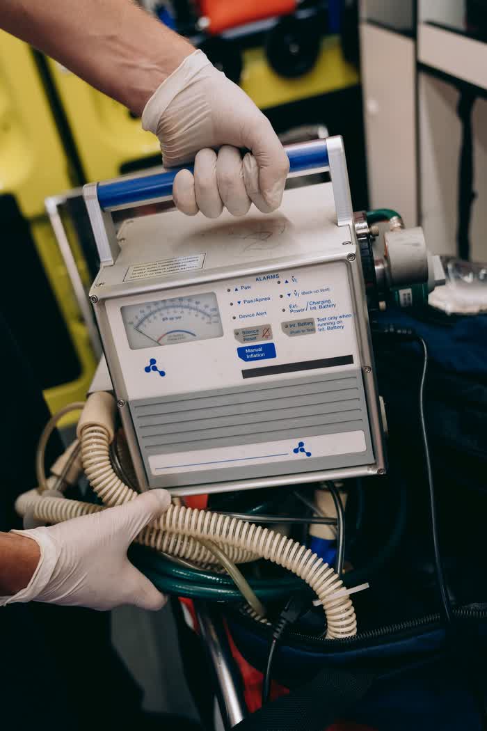 Gloved hands holding a portable ventilator