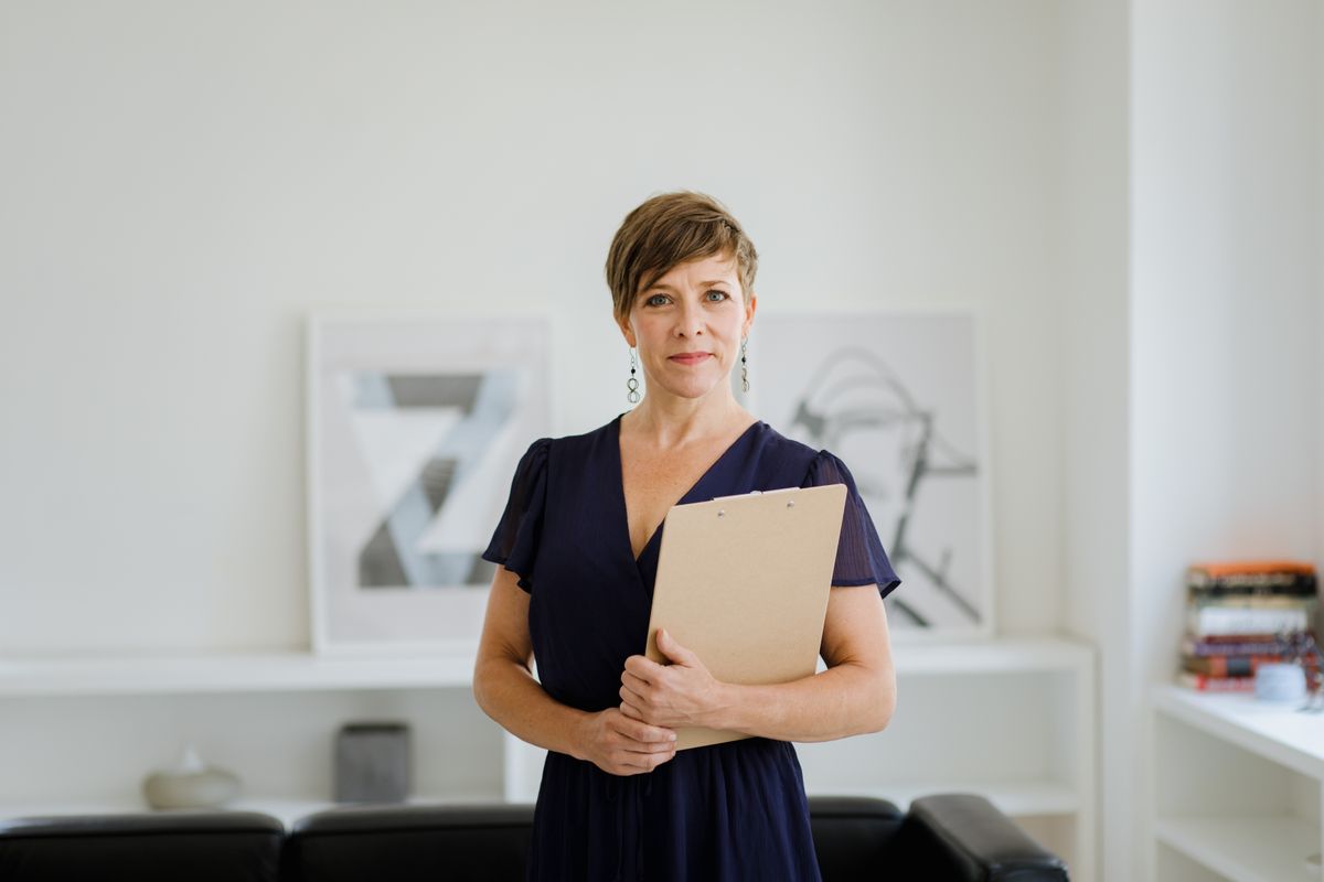 Confident woman with short hair in office setting holding a clipboard